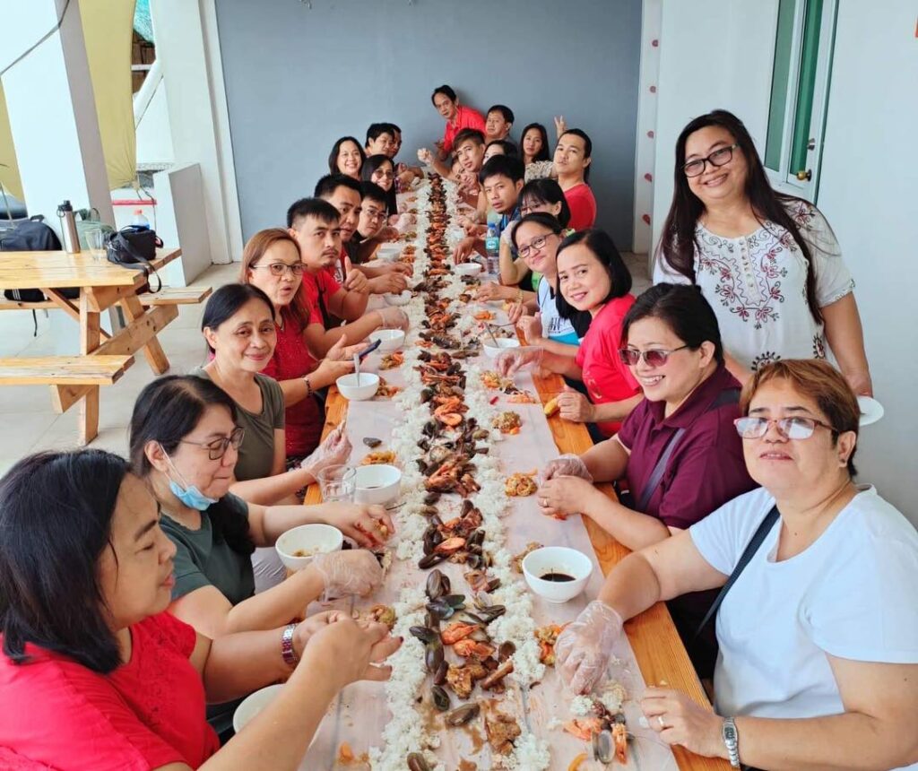 big group of people enjoying eating a boodle fight at the escape hotel san juan